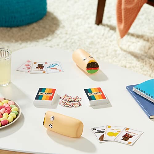 Table with a burrito-themed card game setup. Players are shown with their hands up, ready to throw their burritos.