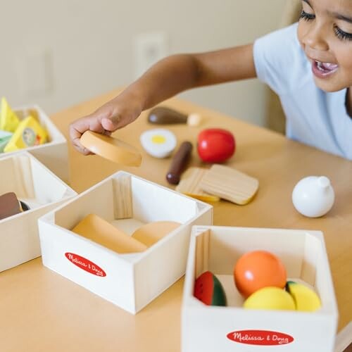 Child playing with toy food and wooden boxes.