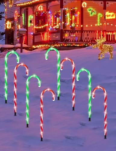 Festive candy cane lights in snow with decorated house