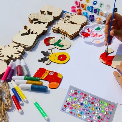 Person painting wooden Christmas decorations with paint and glitter.