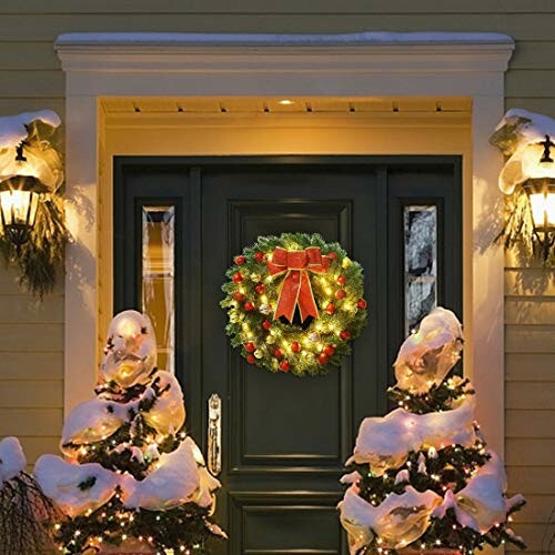 Christmas wreath with lights and red bow on a front door surrounded by snow-covered decorations.