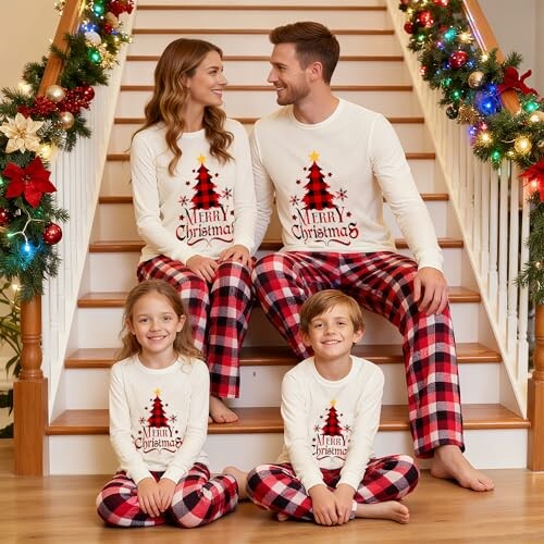 Family in matching Christmas pajamas sitting on decorated stairs.