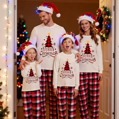 Family wearing matching Christmas pajamas and Santa hats in front of a decorated tree.
