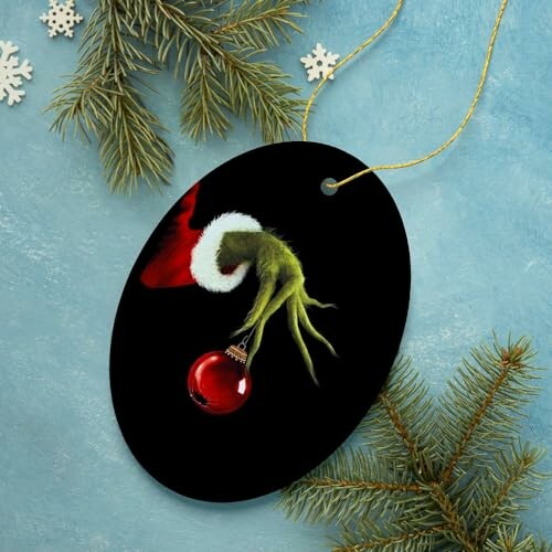Ornament with a green hand holding a red Christmas bauble.