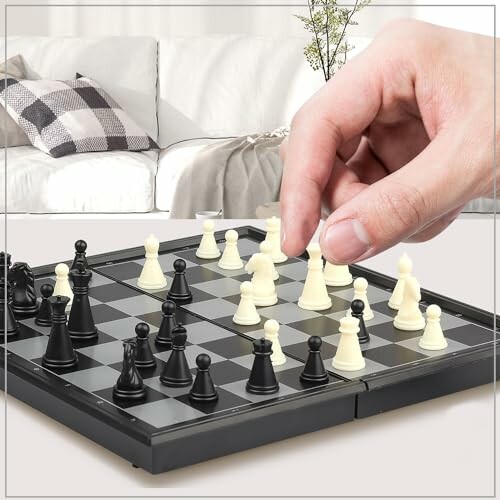 Hand moving a piece on a chessboard in a living room.