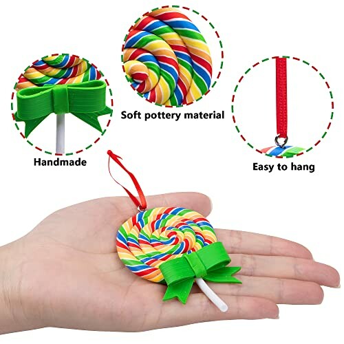 Hand holding a handmade rainbow lollipop ornament with green bow and red hanging ribbon.
