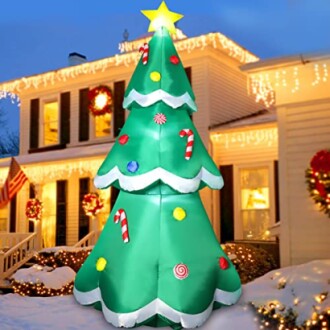 Inflatable Christmas tree with candy and star in snowy yard.
