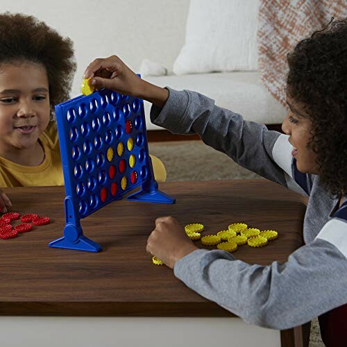 Two children playing Connect Four on a wooden table.