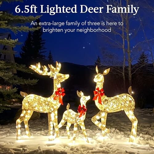 Illuminated deer family decorations in a snowy yard at night.