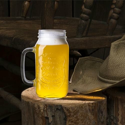 Mason jar with beer on a wooden stump next to a hat.