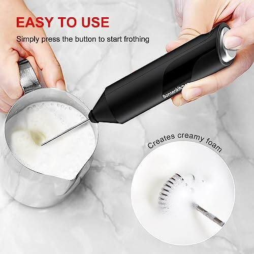 Hand using a milk frother to create creamy foam in a metal pitcher.