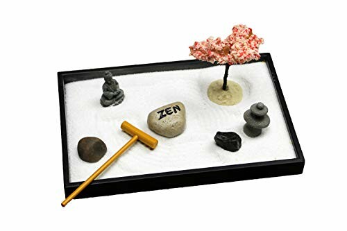 Mini zen garden with sand, stones, miniature tree, and rake.