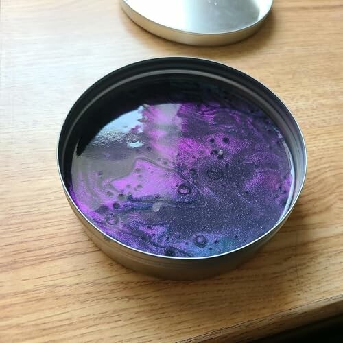 Tin with purple metallic liquid on wooden surface.