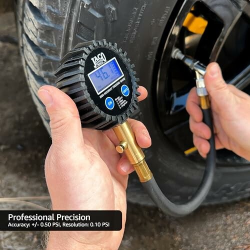 Hands using a digital tire pressure gauge on a car tire.