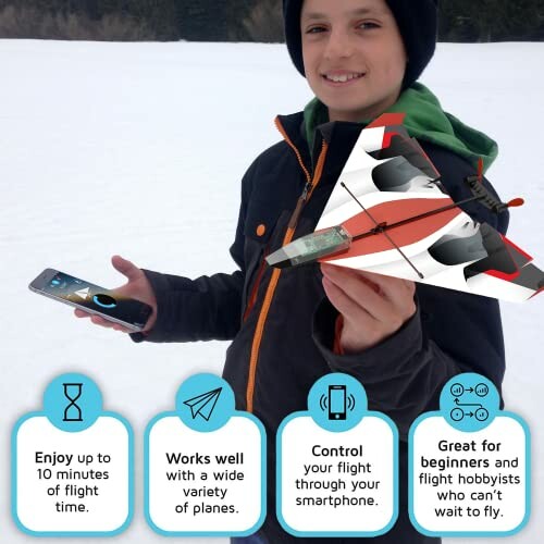 Child holding a smartphone-controlled toy plane in a snowy area.