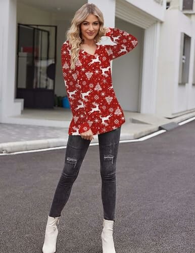 Woman in red Christmas sweater and black jeans standing outdoors.