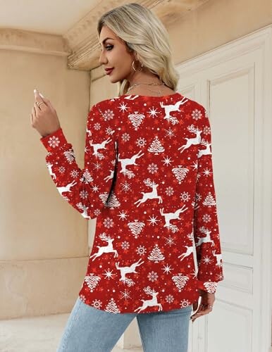 Woman wearing red Christmas-themed sweater with reindeer and snowflakes.