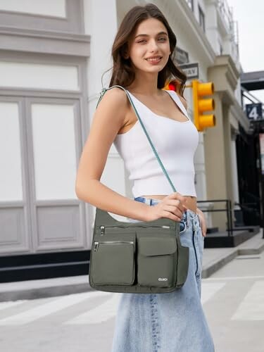 Woman with green shoulder bag wearing a white top and jeans.